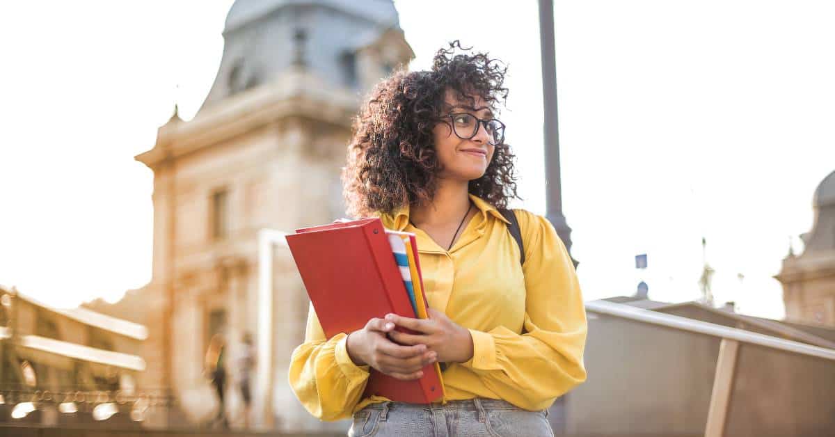 Girl standing on a college campus holding a notebook