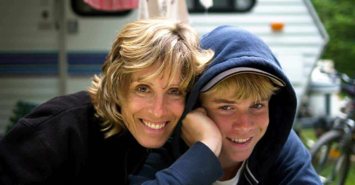 Happy mother side hugging her teen son who has a hoodie on
