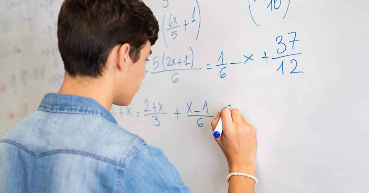 Young man writing a math problem on a white board