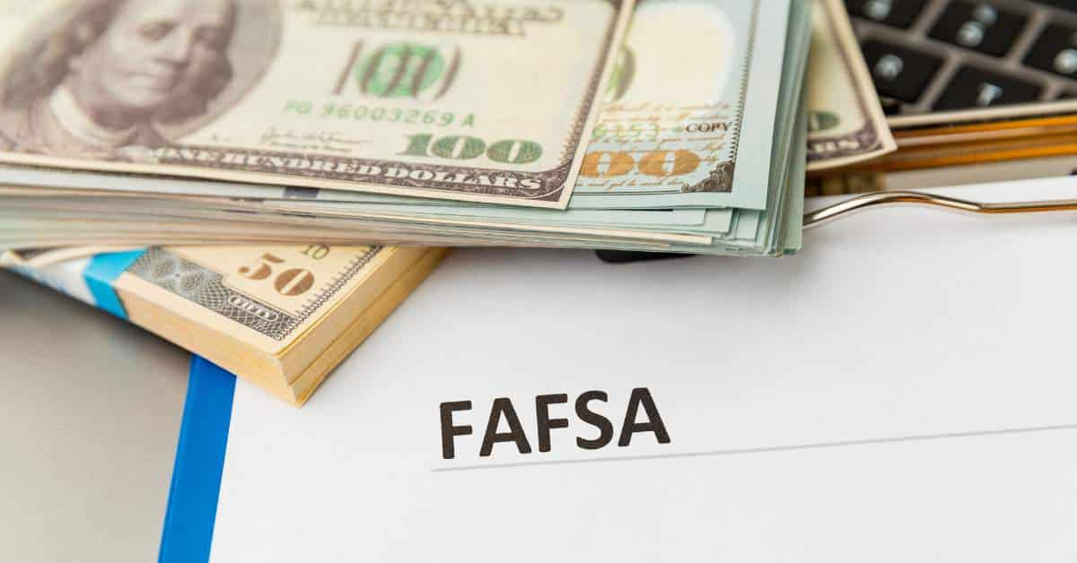 Picture of a piece of white paper with FAFSA written on it and a pile of money off to one side
