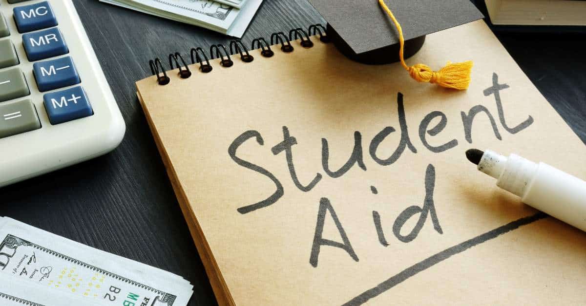 Calculator, money, and a notebook with the words "student aid" written across the front