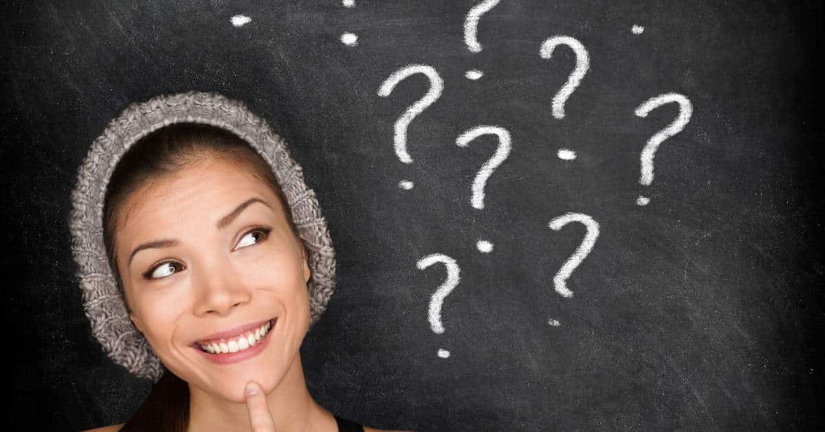Young woman wearing a winter hat looking off to the side where there are a number of question marks