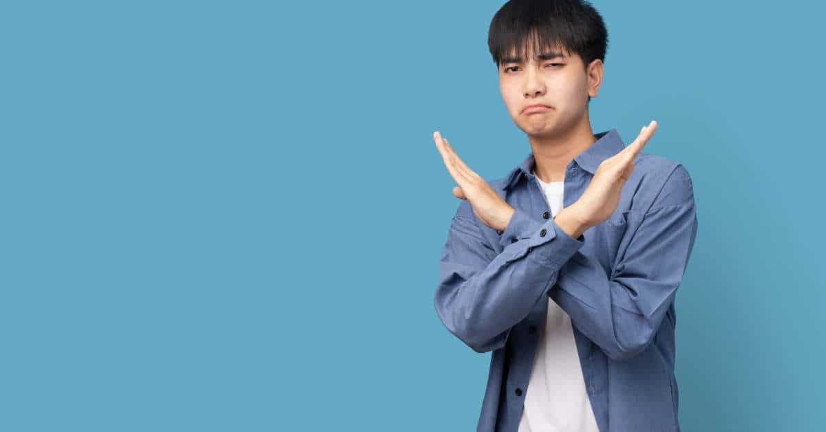 Young man standing with his arms crossed in front of him signifying rejection
