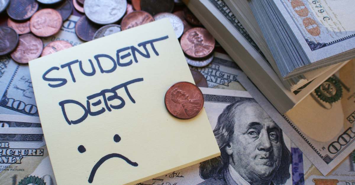 Sticky note with the words, "Student Debt" with a frowny face written on it. In the background is an assortment of US currency.