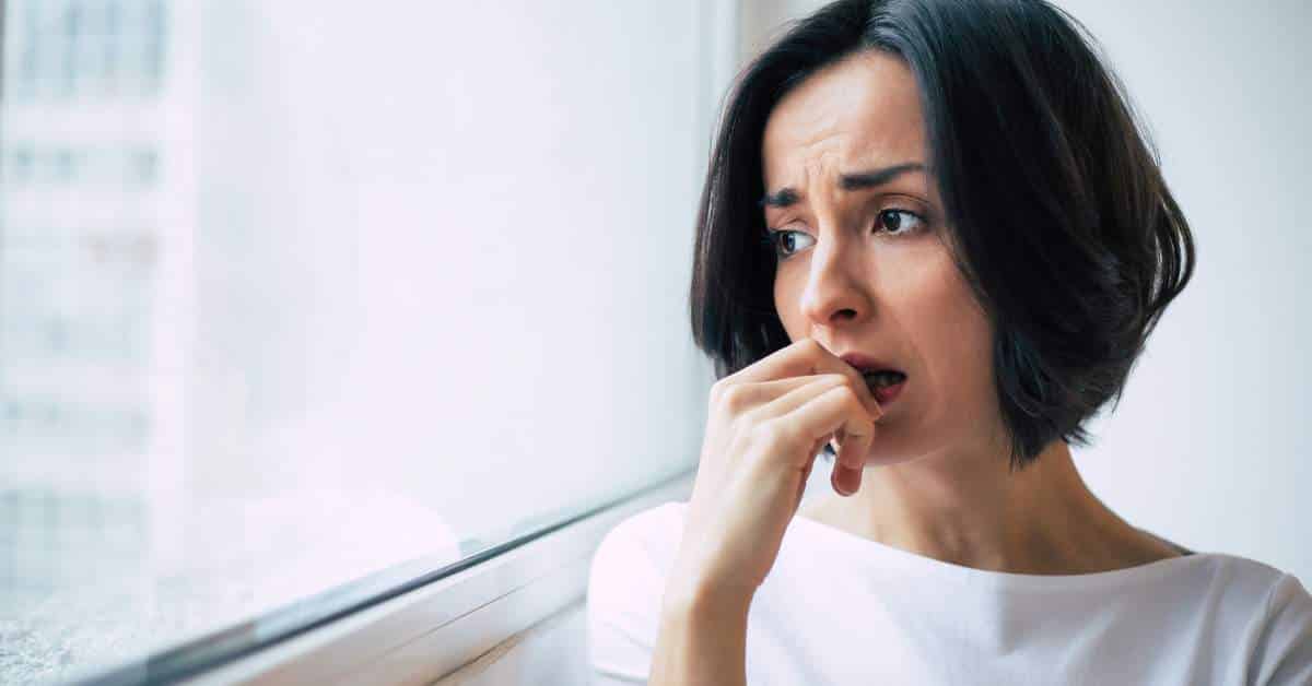 Woman looking out a woman, finger to her mouth, looking concerned