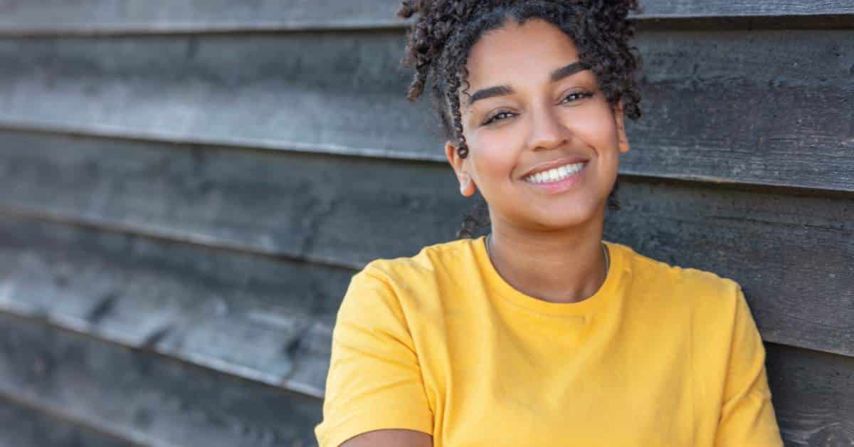 Smiling teen girl wearing a yellow shirt.