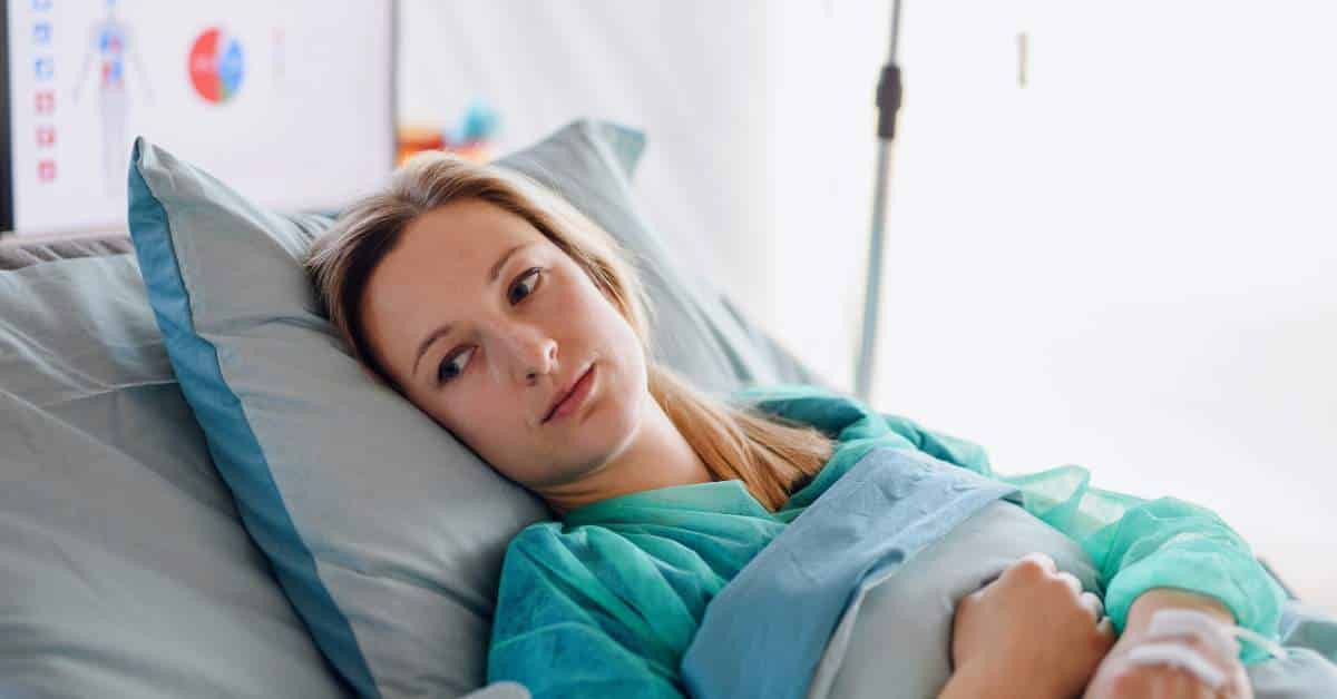 Sick woman laying in bed.
