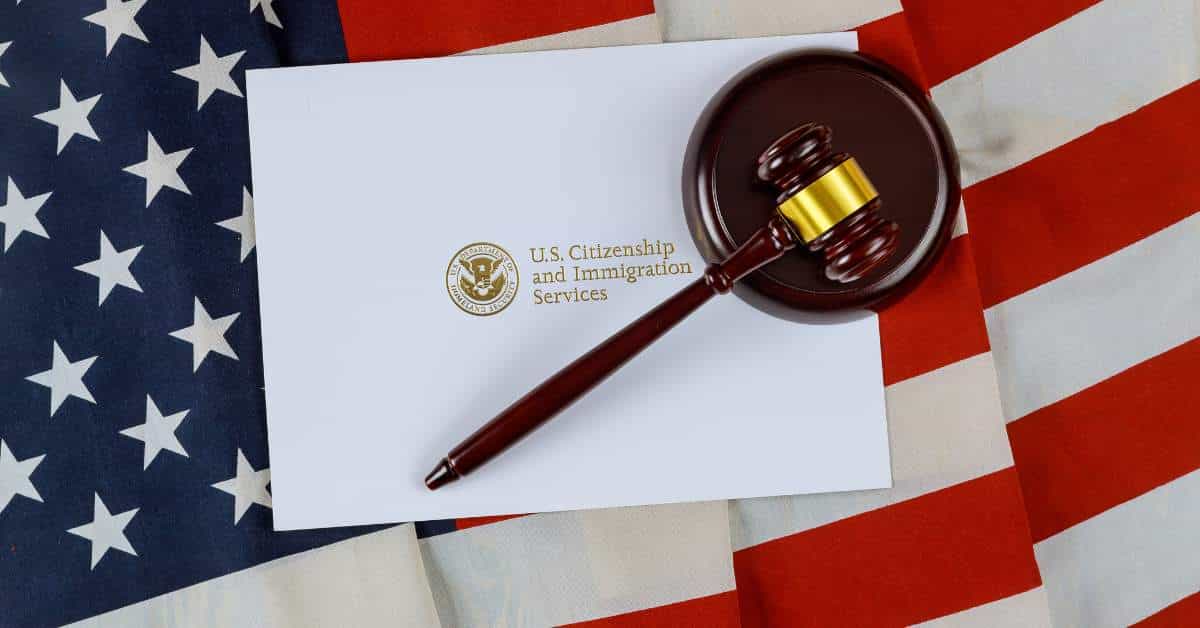 Picture of the American flag with a white paper that reads US Immigration on it and a gavel over that.