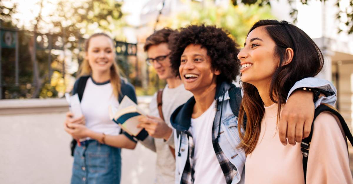 Group of 4 college students walking together and laughing