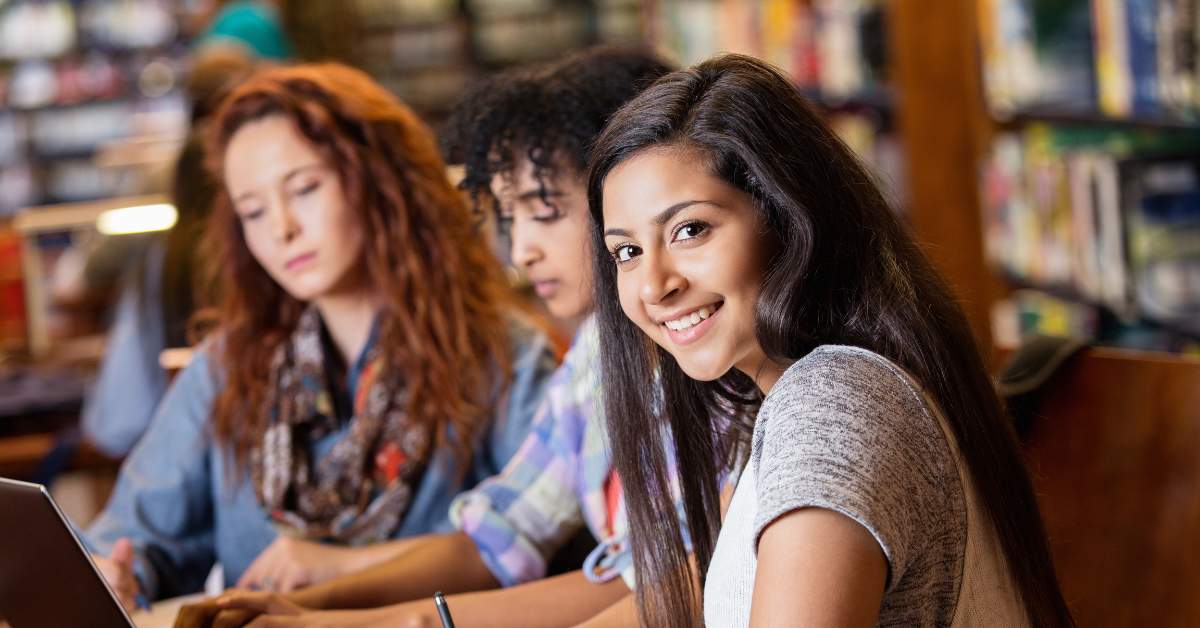 Three college girls working together on a project.